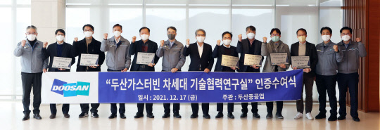 지난 17일 두산중공업 창원 본사에서 열린 '두산가스터빈 차세대 기술협력 연구실' 인증 수여식에서 박홍욱(왼쪽에서 6번째)두산중공업 파워서비스BG장, 손정락(왼쪽에서 7번째) 산업부 R&D 전략기획단 에너지산업 MD를 비롯해 선정된 대학 연구실 교수들이 기념 촬영을 하고 있다. <두산중공업 제공>